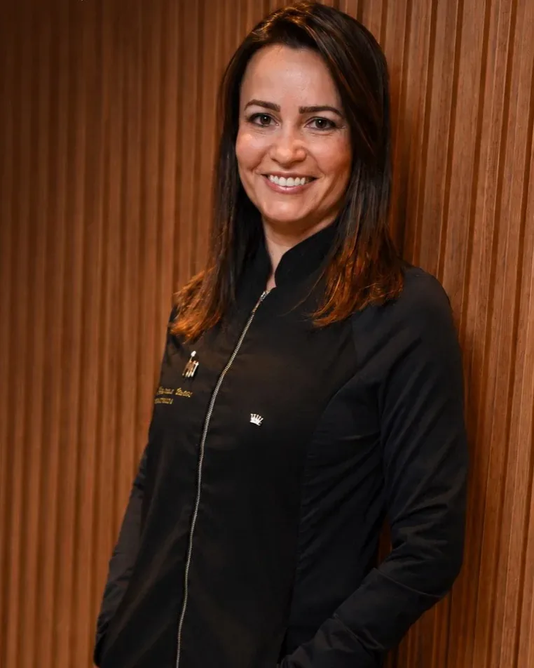 Dra. Marina Bueno, protesista da Vitta, diante do painel de madeira da clínica